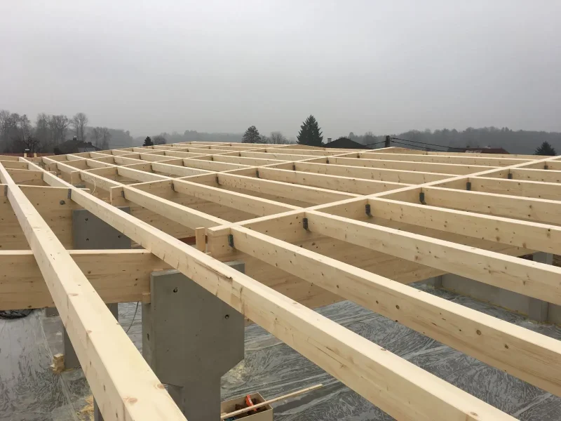 Detailbild einer im Bau befindlichen Halle mit Holz-Dachkonstruktion und Betonstützen.